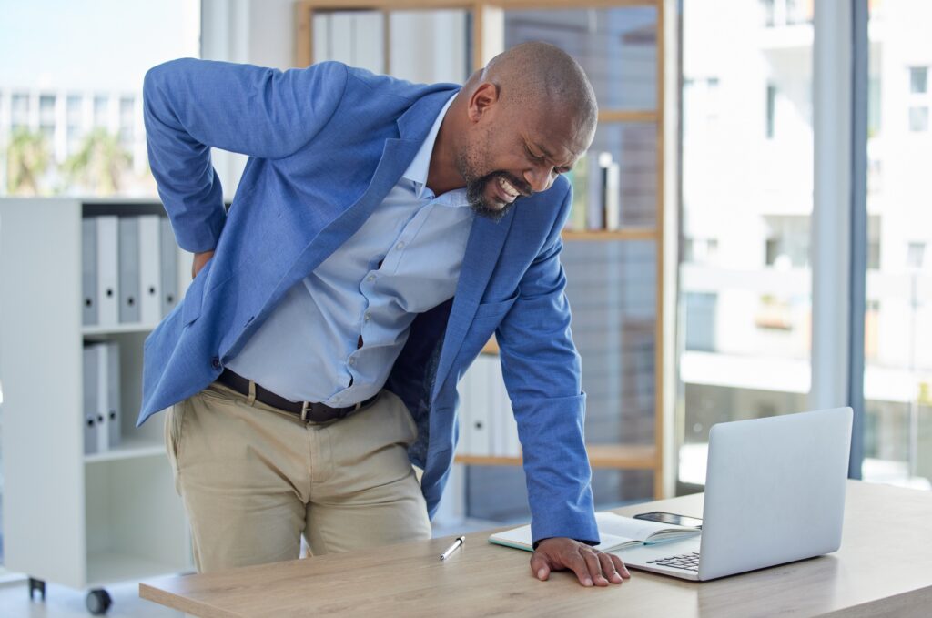 a man in pain and standing at his desk after suffering a back injury at work